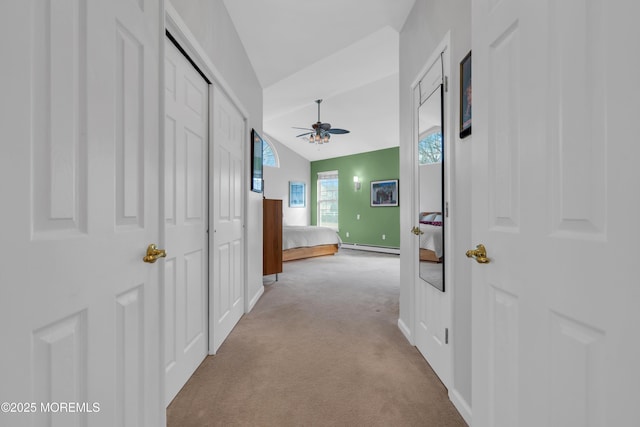 corridor featuring a baseboard heating unit, light carpet, and lofted ceiling