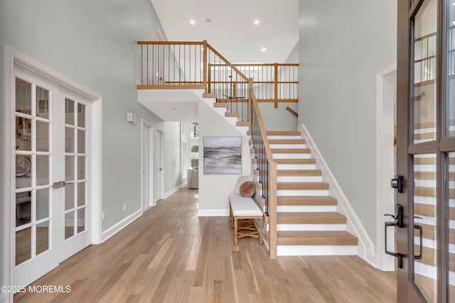 entrance foyer featuring a towering ceiling, light hardwood / wood-style floors, and french doors