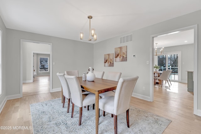 dining space with an inviting chandelier and light hardwood / wood-style floors