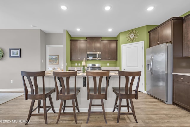 kitchen featuring appliances with stainless steel finishes, dark brown cabinetry, and light hardwood / wood-style floors