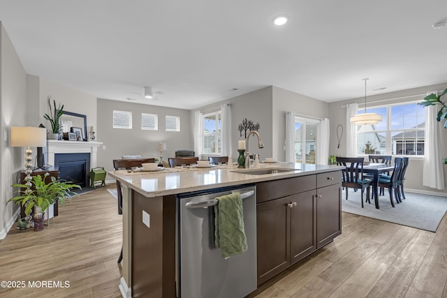 kitchen with a center island with sink, dishwasher, sink, and pendant lighting