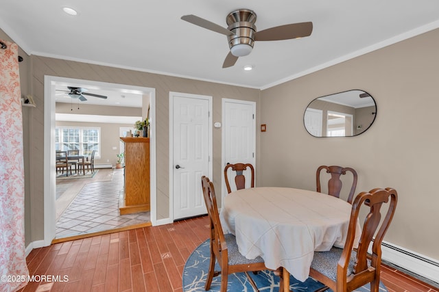 dining space featuring ornamental molding, hardwood / wood-style floors, ceiling fan, and baseboard heating