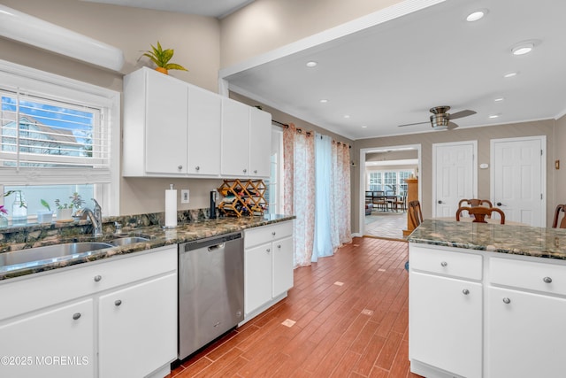 kitchen with sink, white cabinetry, a wealth of natural light, stainless steel dishwasher, and dark stone counters