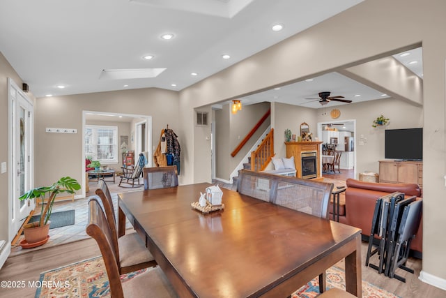 dining room featuring lofted ceiling with skylight, ceiling fan, and light hardwood / wood-style floors