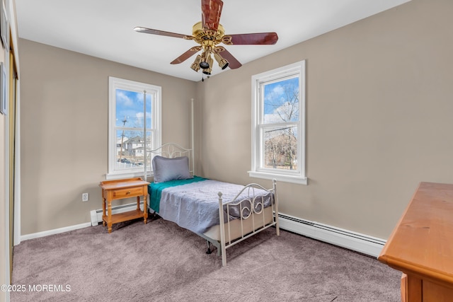 carpeted bedroom with ceiling fan, multiple windows, and a baseboard heating unit