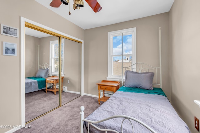 carpeted bedroom with ceiling fan, multiple windows, a baseboard radiator, and a closet