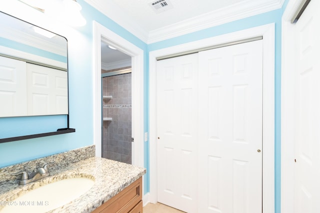 bathroom with crown molding, a tile shower, and vanity