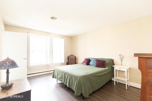 bedroom with dark hardwood / wood-style floors, a textured ceiling, and baseboard heating