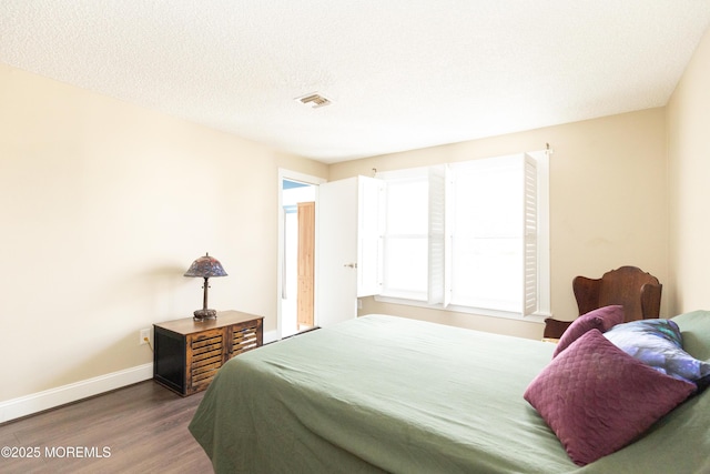 bedroom with dark hardwood / wood-style floors and a textured ceiling