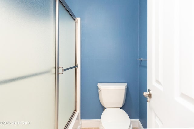 bathroom with a shower with shower door and toilet