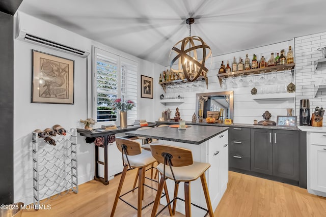 kitchen with decorative light fixtures, gray cabinets, a kitchen island, light hardwood / wood-style floors, and white cabinets