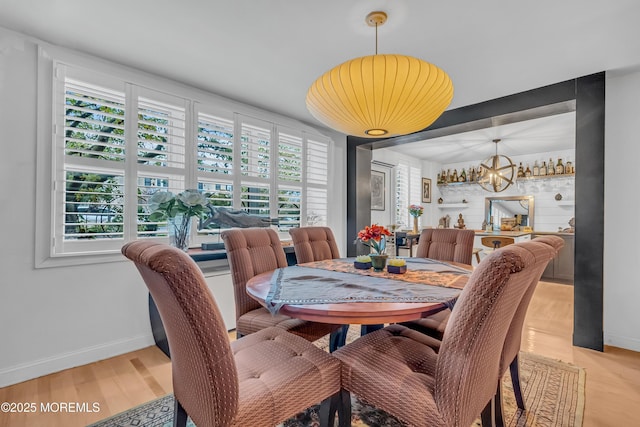 dining space featuring a healthy amount of sunlight, a chandelier, and light wood-type flooring