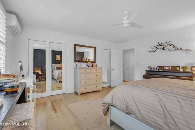 bedroom featuring french doors, light hardwood / wood-style flooring, an AC wall unit, two closets, and ceiling fan