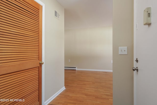 corridor with light hardwood / wood-style floors and a baseboard heating unit