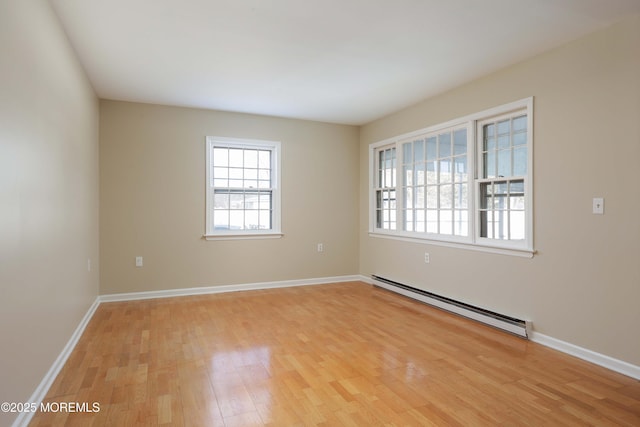 spare room with a baseboard heating unit and light wood-type flooring