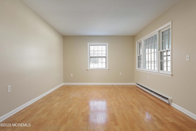 empty room with a baseboard heating unit and light hardwood / wood-style floors