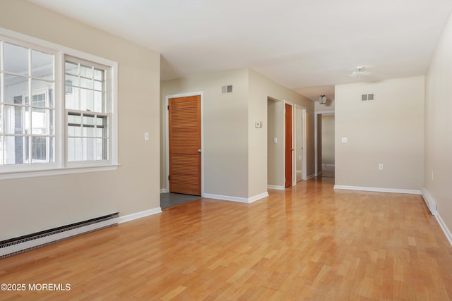 empty room featuring a baseboard radiator and light wood-type flooring