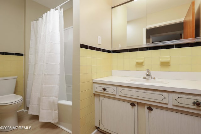 full bathroom with toilet, tile walls, vanity, shower / bath combination with curtain, and hardwood / wood-style floors