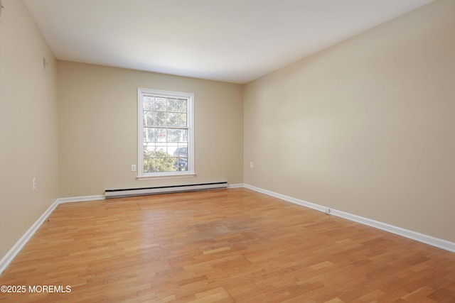 empty room featuring a baseboard heating unit and light wood-type flooring