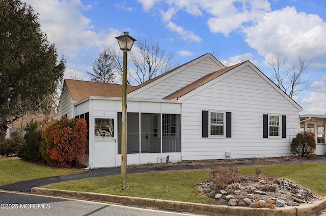 view of front of home featuring a sunroom and a front lawn