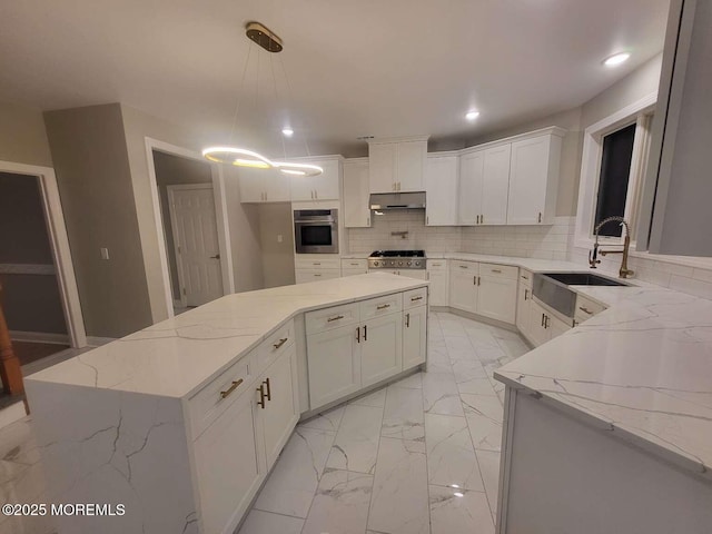 kitchen featuring sink, decorative light fixtures, appliances with stainless steel finishes, a kitchen island, and light stone countertops