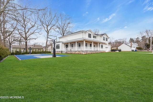 rear view of property featuring basketball court and a lawn