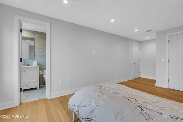 bedroom featuring connected bathroom and light wood-type flooring