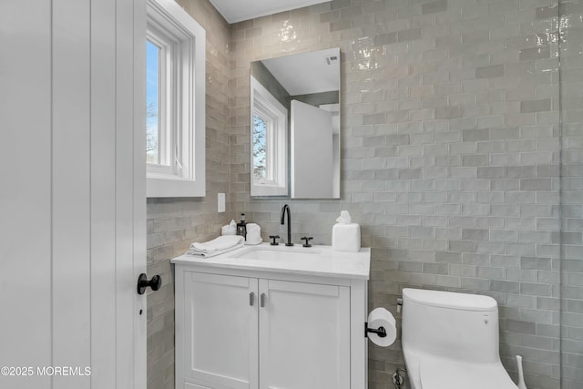 bathroom with vanity, tile walls, and toilet