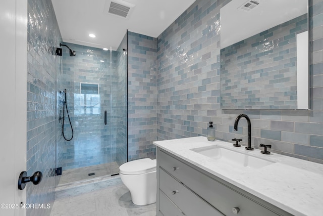 bathroom featuring a shower with door, tile walls, vanity, decorative backsplash, and toilet