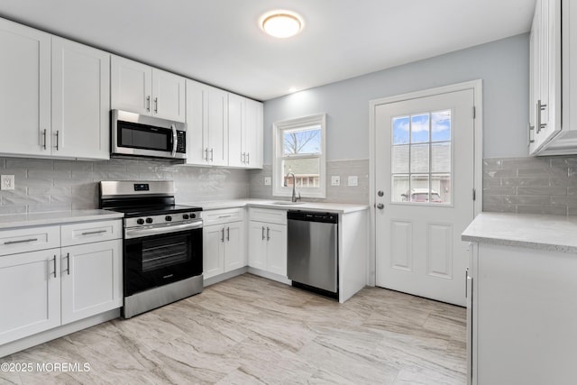 kitchen featuring appliances with stainless steel finishes, sink, white cabinets, and decorative backsplash