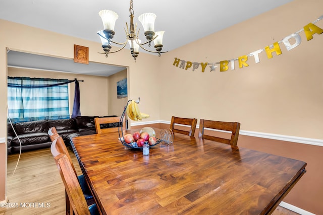 dining space featuring wood-type flooring and a notable chandelier