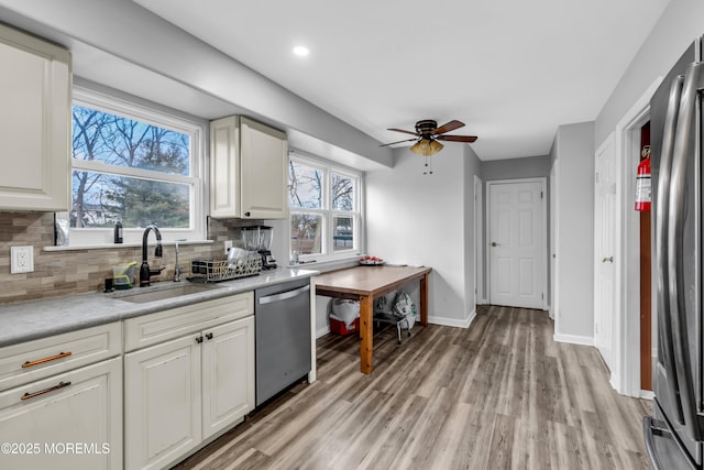 kitchen with sink, ceiling fan, backsplash, stainless steel appliances, and light hardwood / wood-style floors