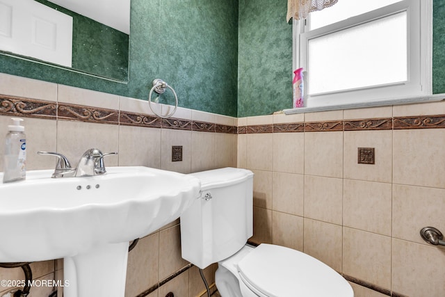 bathroom with tile walls, sink, and toilet