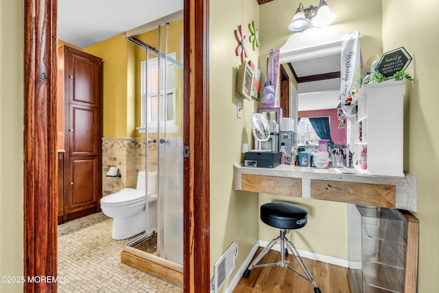 bathroom featuring tile walls, tile patterned floors, and toilet