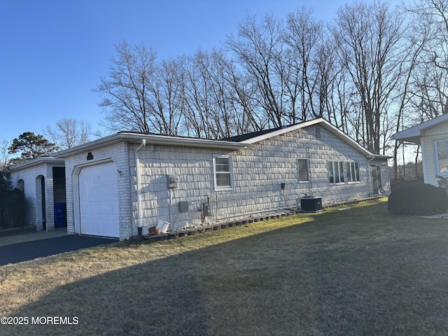 view of side of home featuring cooling unit, a lawn, and a garage