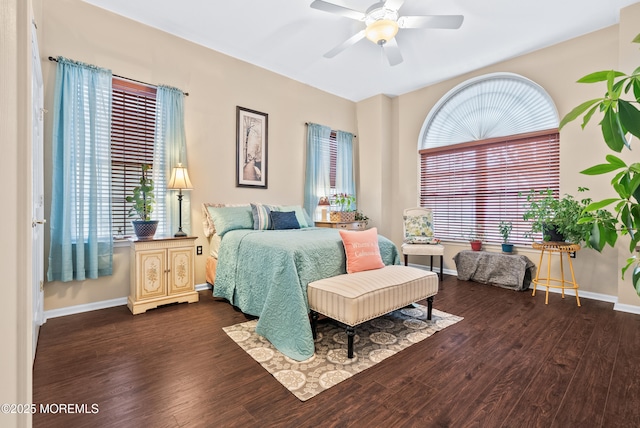 bedroom featuring a ceiling fan, multiple windows, baseboards, and dark wood-style flooring