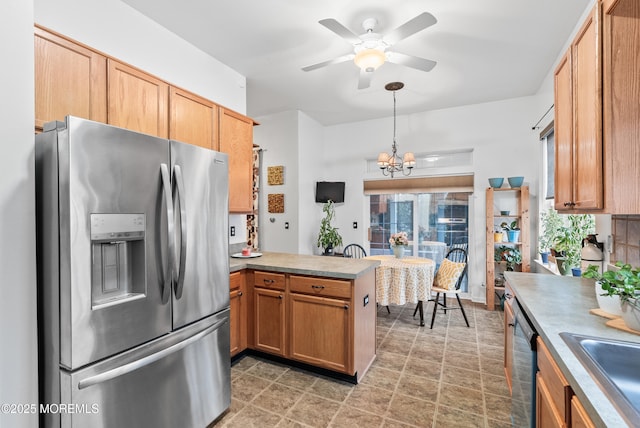 kitchen with stainless steel fridge, black dishwasher, a peninsula, light countertops, and a sink