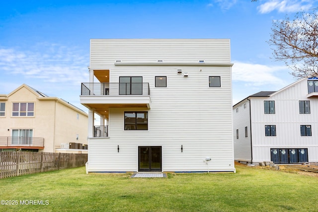 rear view of house with a yard, fence, and a balcony