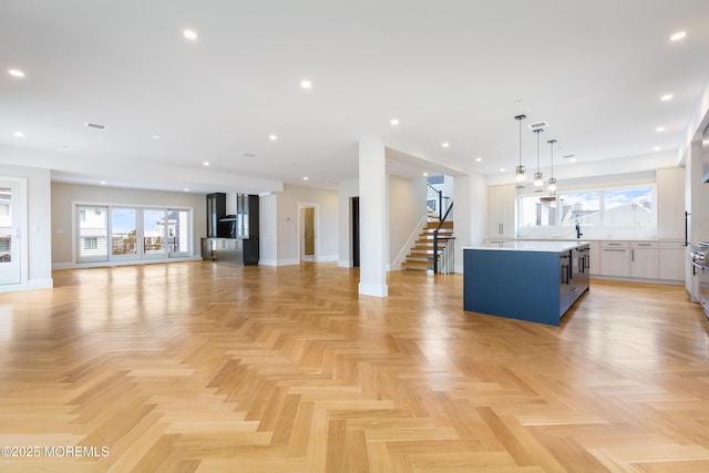 unfurnished living room with recessed lighting, stairway, and baseboards