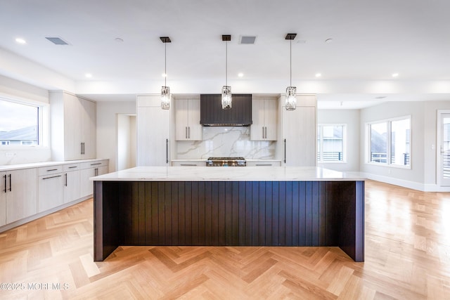 kitchen featuring tasteful backsplash, visible vents, a large island, modern cabinets, and decorative light fixtures