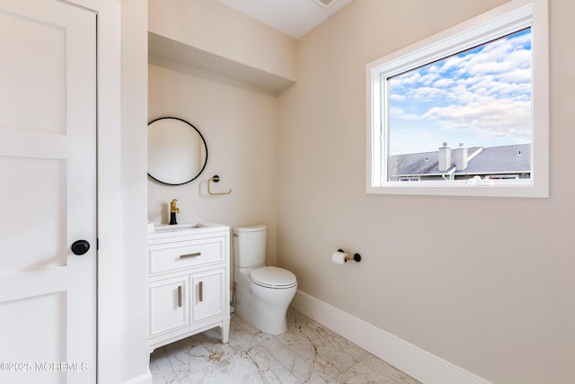 half bath featuring toilet, marble finish floor, baseboards, and vanity