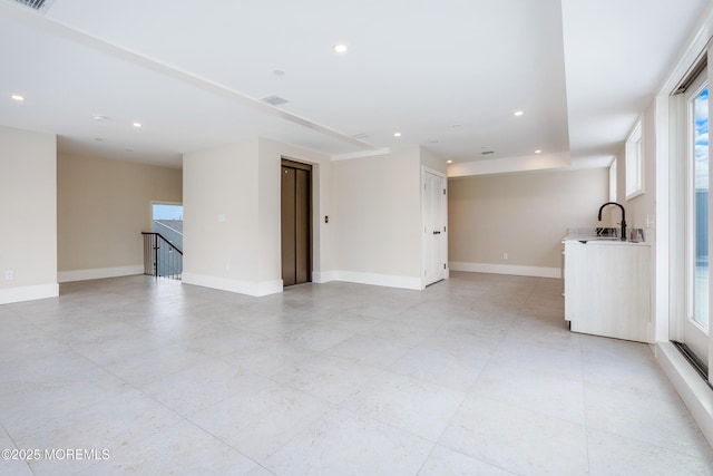 unfurnished room with visible vents, baseboards, elevator, a sink, and recessed lighting