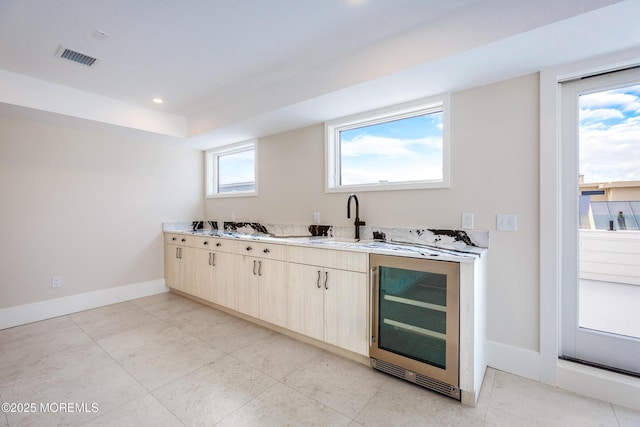 kitchen featuring beverage cooler, a sink, visible vents, baseboards, and light countertops