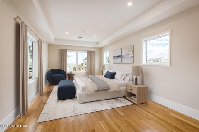 bedroom featuring visible vents, baseboards, a raised ceiling, light wood-type flooring, and recessed lighting