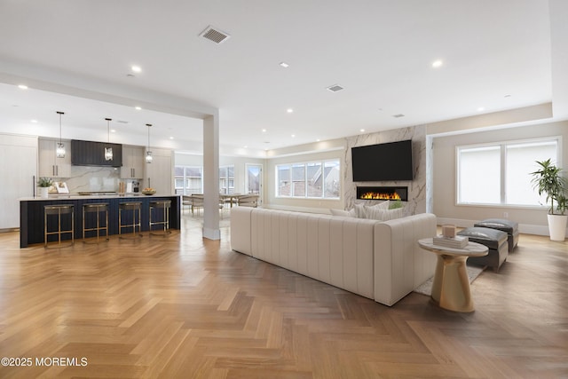 living area with a high end fireplace, visible vents, and recessed lighting