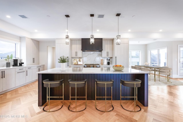 kitchen featuring hanging light fixtures, a spacious island, modern cabinets, and light countertops