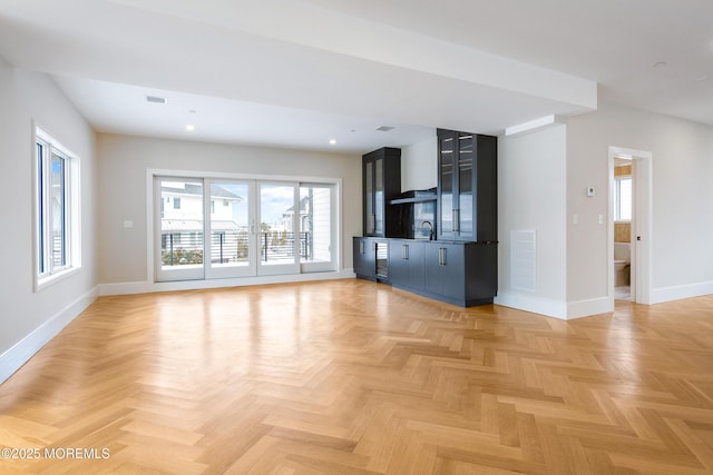 unfurnished living room featuring visible vents, baseboards, a sink, and recessed lighting