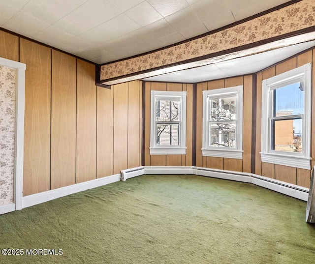 unfurnished room featuring wood walls, a baseboard heating unit, and carpet floors