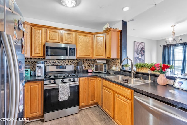 kitchen with light wood-type flooring, appliances with stainless steel finishes, sink, and backsplash