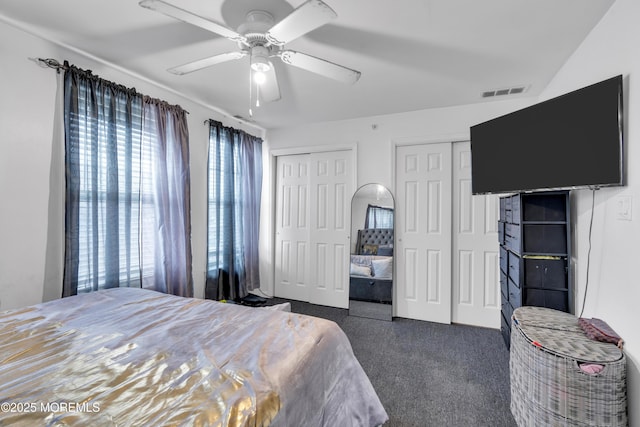 carpeted bedroom featuring multiple closets and ceiling fan